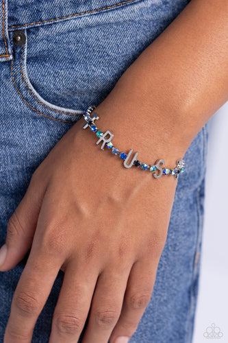 Set in silver square fittings, various multicolored rhinestones gleam around the wrist. Infused along the design, sleek silver letters spell out the word 