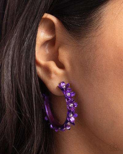 Dipped in a purple hue, a hollowed-out hoop curls around the ear. Featuring silver beaded centers, metallic purple flowers bloom along the curl of the hollow of the hoop for a fashionable display. Earring attaches to a standard post fitting. Hoop measures approximately 1 1/4