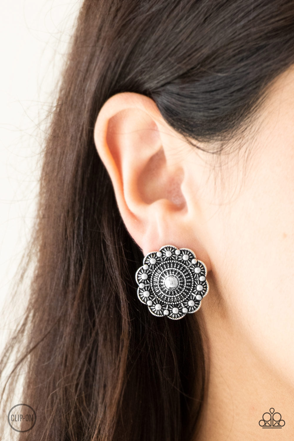 Brushed in an antiqued shimmer, a studded silver floral frame radiates with rippling textures for a seasonal fashion. Earring attaches to a standard clip-on fitting. Sold as one pair of clip-on earrings.