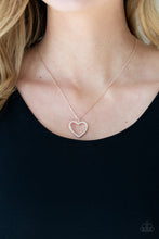 Load image into Gallery viewer, Encrusted in sparkly rhinestones, an airy shiny rose gold heart frame swings from a dainty shiny rose gold chain below the collar for a romantic look. Features an adjustable clasp closure.  Sold as one individual necklace. Includes one pair of matching earrings.
