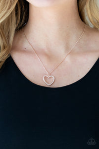 Encrusted in sparkly rhinestones, an airy shiny rose gold heart frame swings from a dainty shiny rose gold chain below the collar for a romantic look. Features an adjustable clasp closure.  Sold as one individual necklace. Includes one pair of matching earrings.